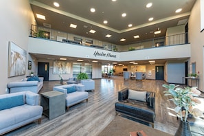 A spacious lobby with multiple seating areas, a central staircase, and a mezzanine level.