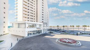 A modern hotel with a central courtyard, a parking area, and a view of the beach. - Delightful 2 bedroom condo Encantame Towers Verano 705 (Puerto Peñasco)