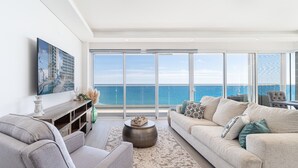 A spacious living room with a large balcony overlooking the ocean, a flat-screen TV mounted on the wall, and a comfortable seating area with a sofa and armchairs. - Delightful 2 bedroom condo Encantame Towers Verano 705 (Puerto Peñasco)