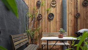 Een houten bankje en tafel tegen een houten muur met metalen wielen.