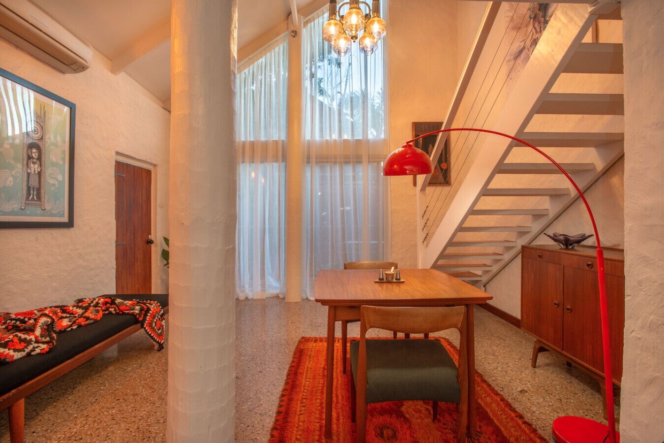 A cozy room with a wooden table, a bench, and a staircase.