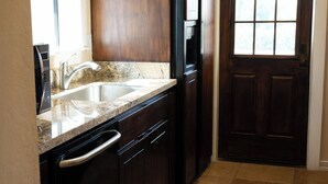 A kitchen with dark wooden cabinets, a stainless steel sink, and a tiled floor. - Carefree Paradise (Carefree)