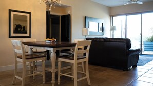 A dining area with a table and chairs, a chandelier, a black sofa, and a large window. - Carefree Paradise (Carefree)