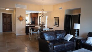 A living room with a leather sofa, a dining table, and chairs. There is a chandelier hanging from the ceiling. - Carefree Paradise (Carefree)