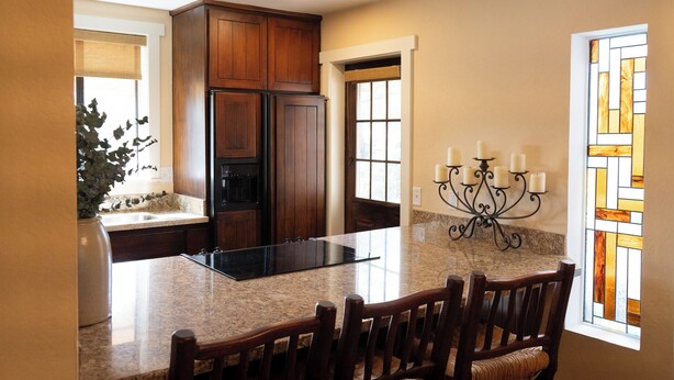 A kitchen with granite countertops, wooden cabinets, a built-in island, and a chandelier. - Carefree Paradise (Carefree)
