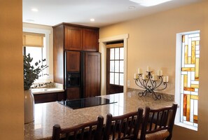 A kitchen with granite countertops, wooden cabinets, a built-in island, and a chandelier. - Carefree Paradise (Carefree)