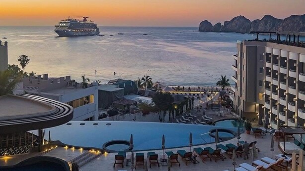 A resort with a pool area, lounge chairs, and a view of the sea and a cruise ship. - Corazon Cabo, Infinty Two Queen Sunset View Hot Tub, Spend New Year's in Cabo (Cabo San Lucas)