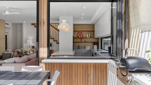 Een moderne keuken met een groot raam, houten lambrisering en een eethoek met tafel en stoelen.