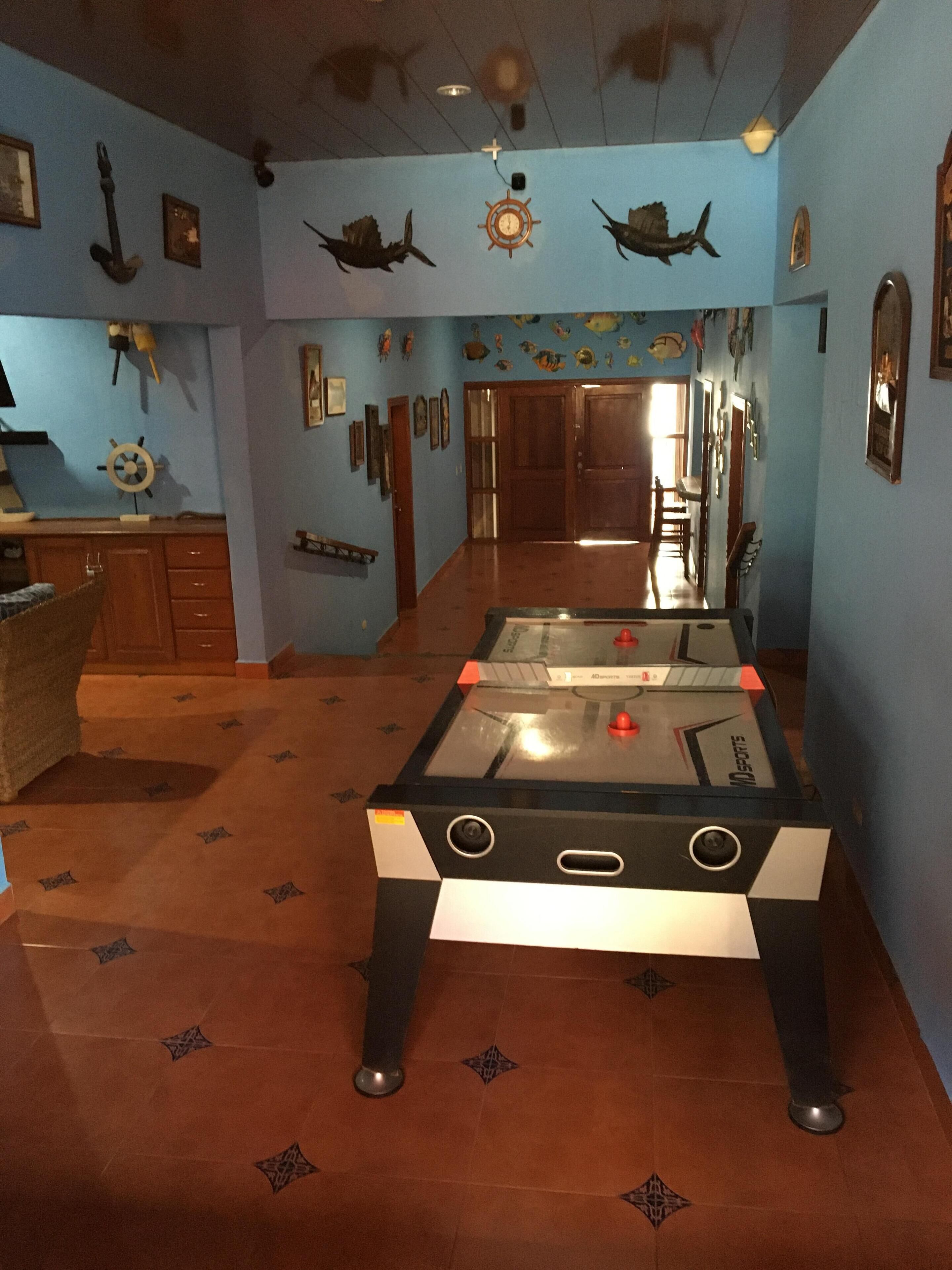 A room with a foosball table, wooden cabinets, and a ceiling fan.