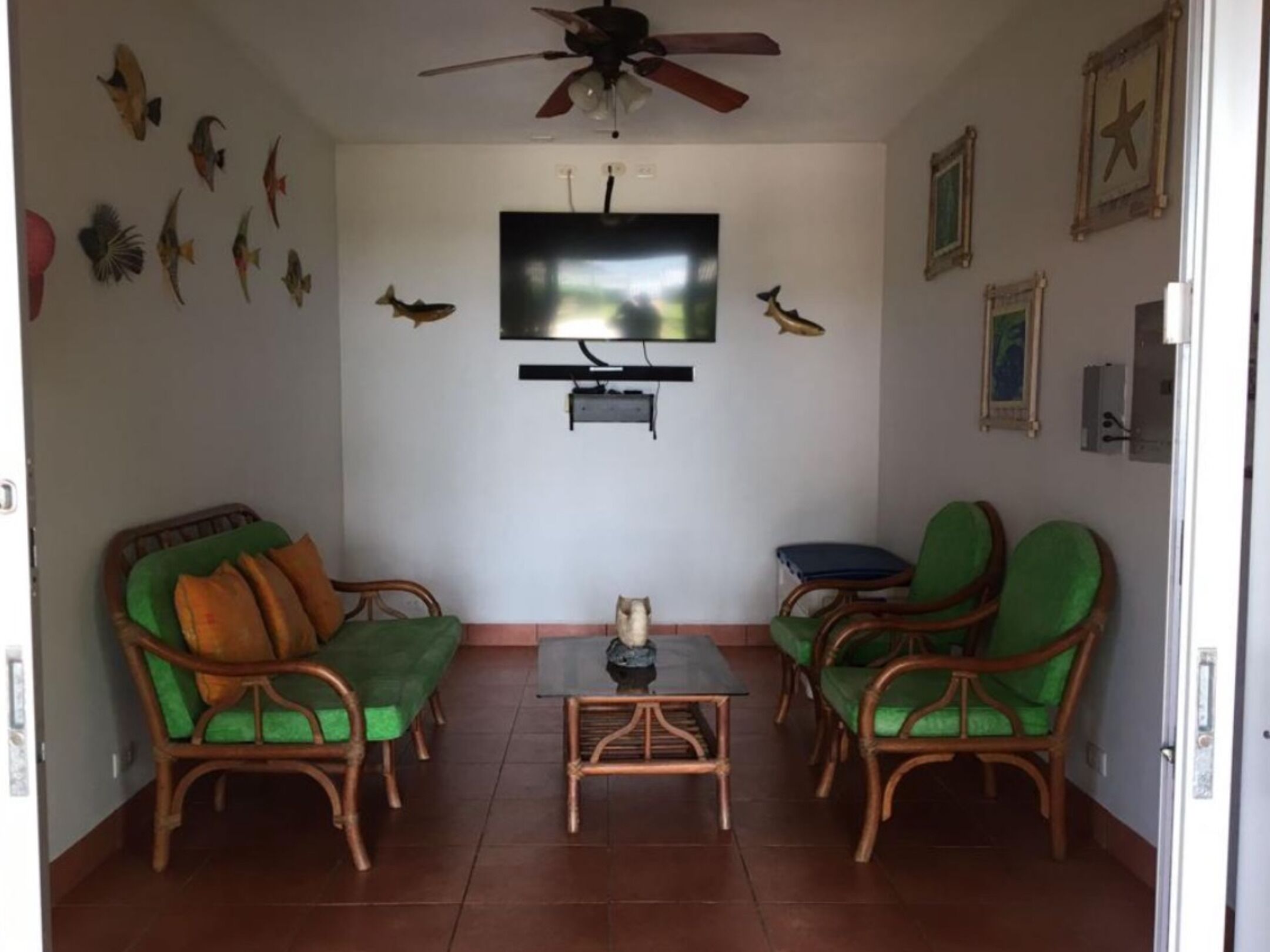 Ein Wohnzimmer mit Fernseher, Korbmöbeln und Wanddekorationen.