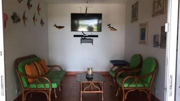 Ein Wohnzimmer mit Fernseher, Korbmöbeln und Wanddekorationen.