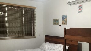A bedroom with a wooden bed, a window with blinds, an air conditioner, and a ceiling fan. -  Beach Front House in Tránsito Beach , 5-Bedrooms, AC ,with Beachfront  Pool. (El Tránsito)