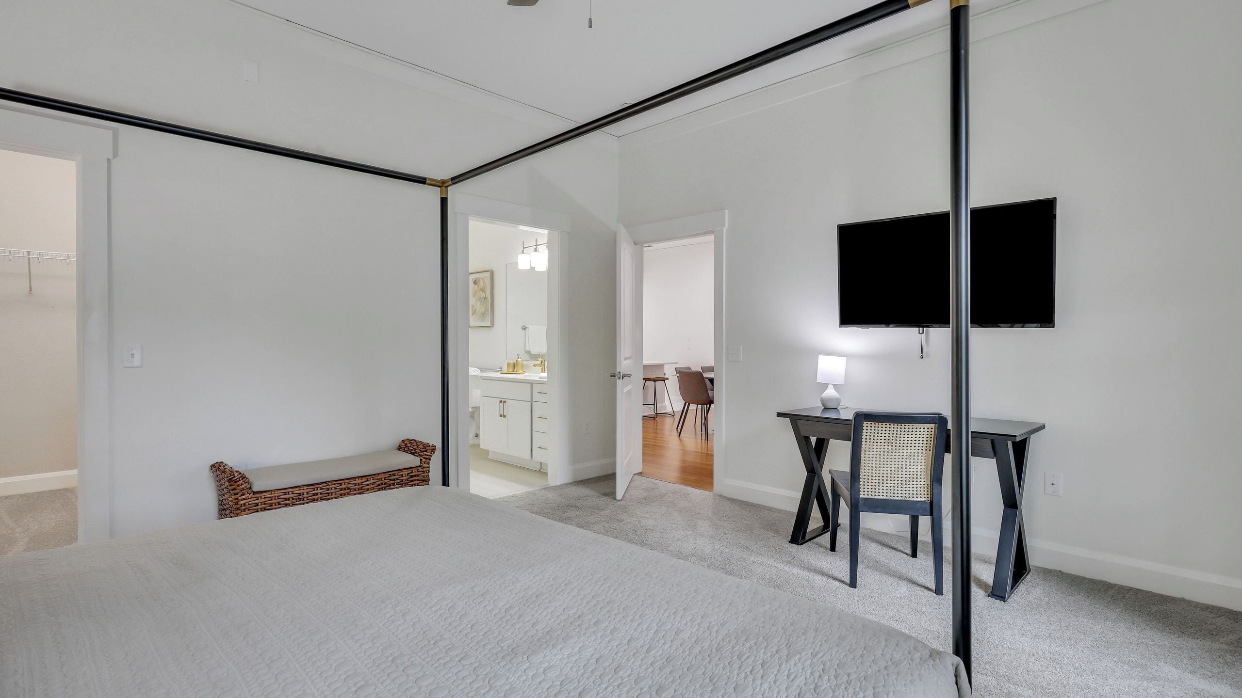 A modern bedroom with a large bed, a desk, a chair, and a TV.