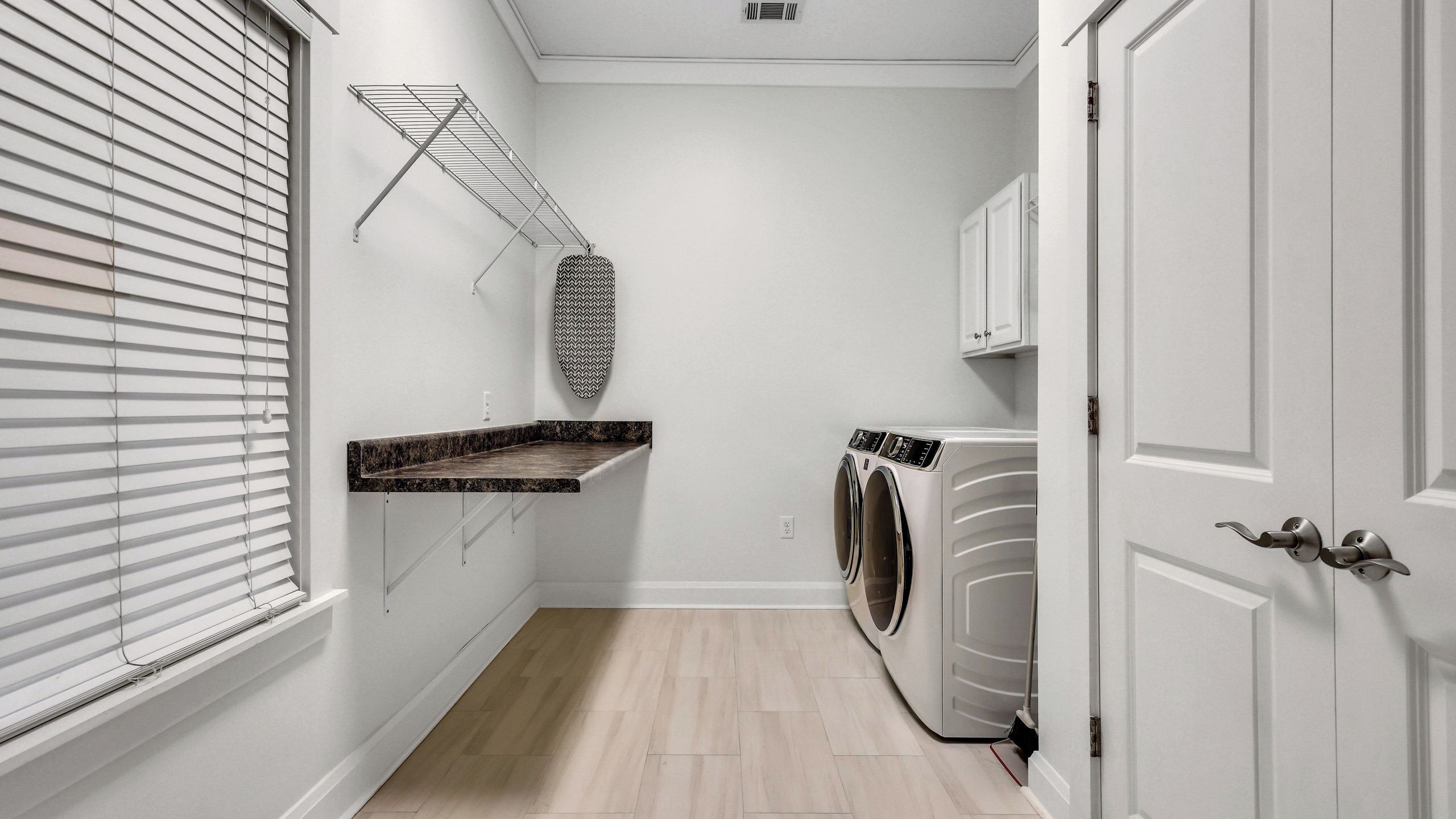 A laundry room with a washing machine, a drying rack, and a shelf.