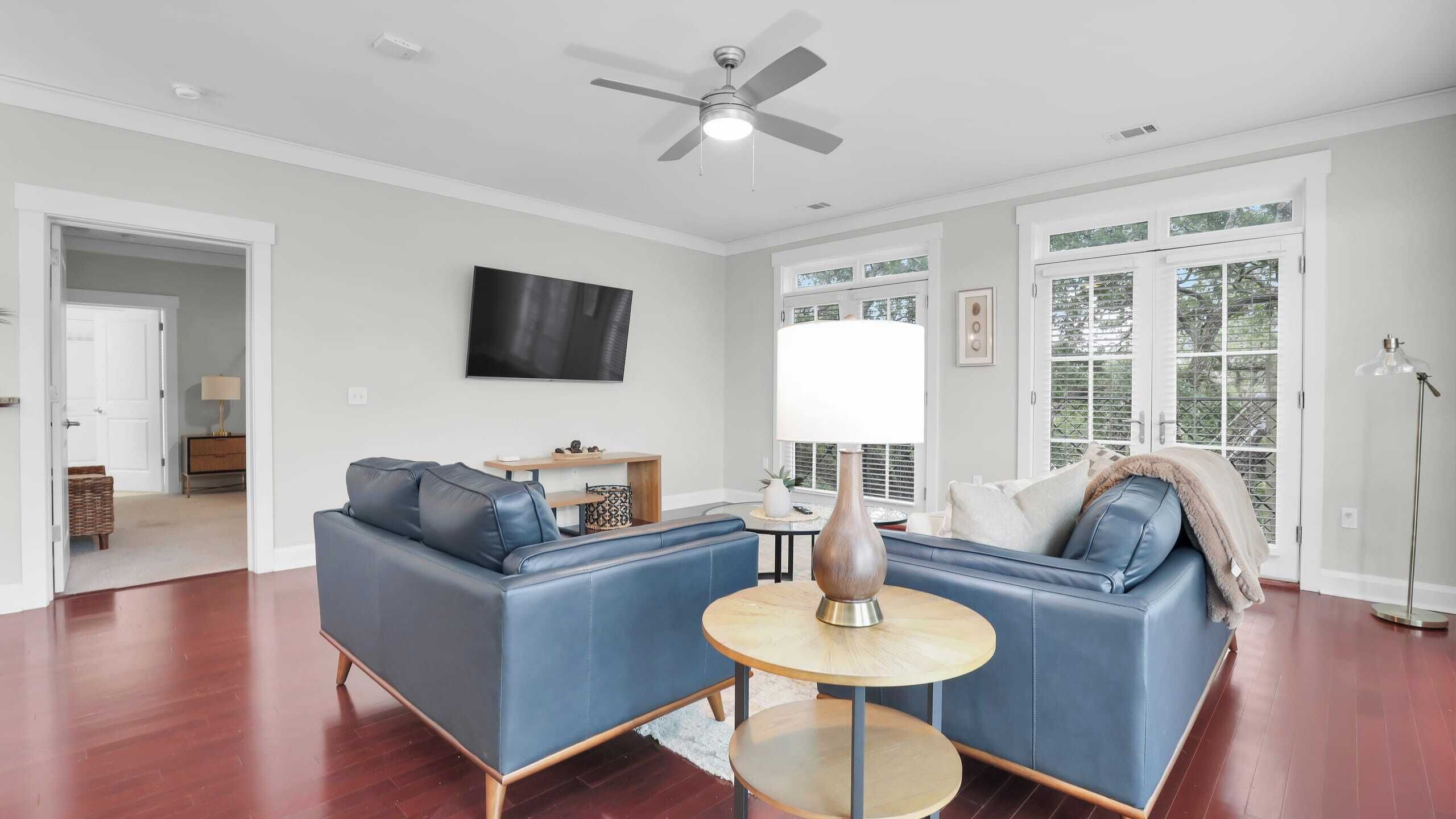 A spacious living room with a blue sofa, a coffee table, and a ceiling fan.
