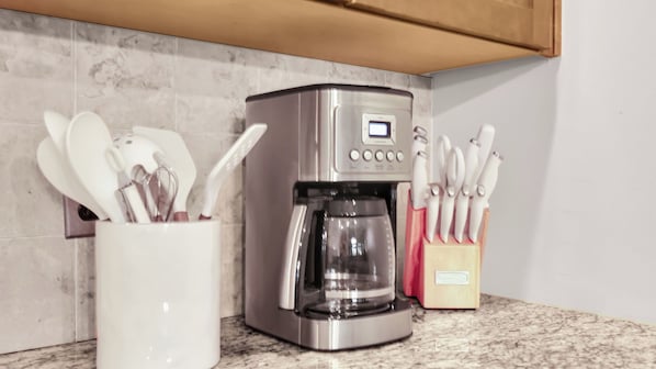 A kitchen with a coffee maker, a utensil holder, and a knife block. - The Juliette by AvantStay (Savannah)