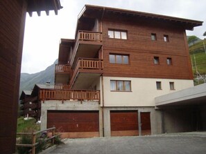 A multi-story wooden building with balconies, a garage, and a view of mountains. - Very comfortable 3-room apartment for 3-4 persons : Living room - kitchen with dishwasher, filter co (Grimentz)