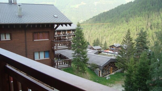 A mountain lodge with multiple floors, wooden balconies, and a view of a forested valley. - Very comfortable 3-room apartment for 3-4 persons : Living room - kitchen with dishwasher, filter co (Grimentz)