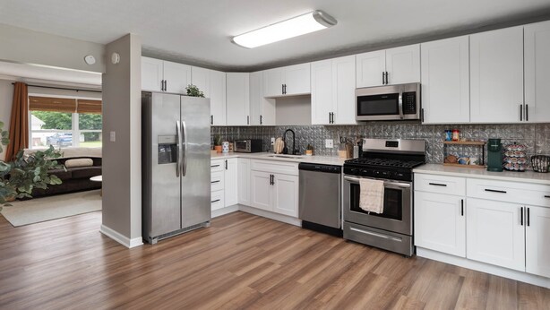 A modern kitchen with white cabinets, stainless steel appliances, and a wooden floor. - Cozy Ranch King Bed & Pet Friendly - Fenced Yard (Gahanna)