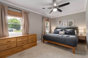 A bedroom with a bed, wooden dresser, ceiling fan, and artwork on the wall. - Cozy Ranch King Bed & Pet Friendly - Fenced Yard (Gahanna)