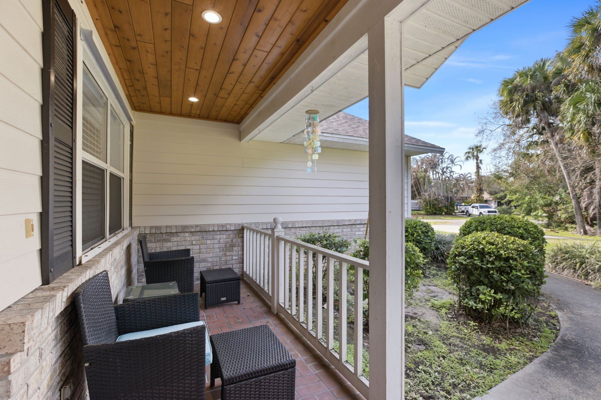 A covered porch with wicker furniture and a view of the surrounding area.