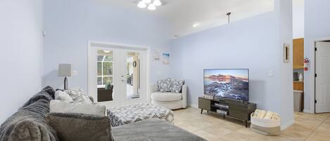 A living room with a sofa, a TV, and a ceiling fan.