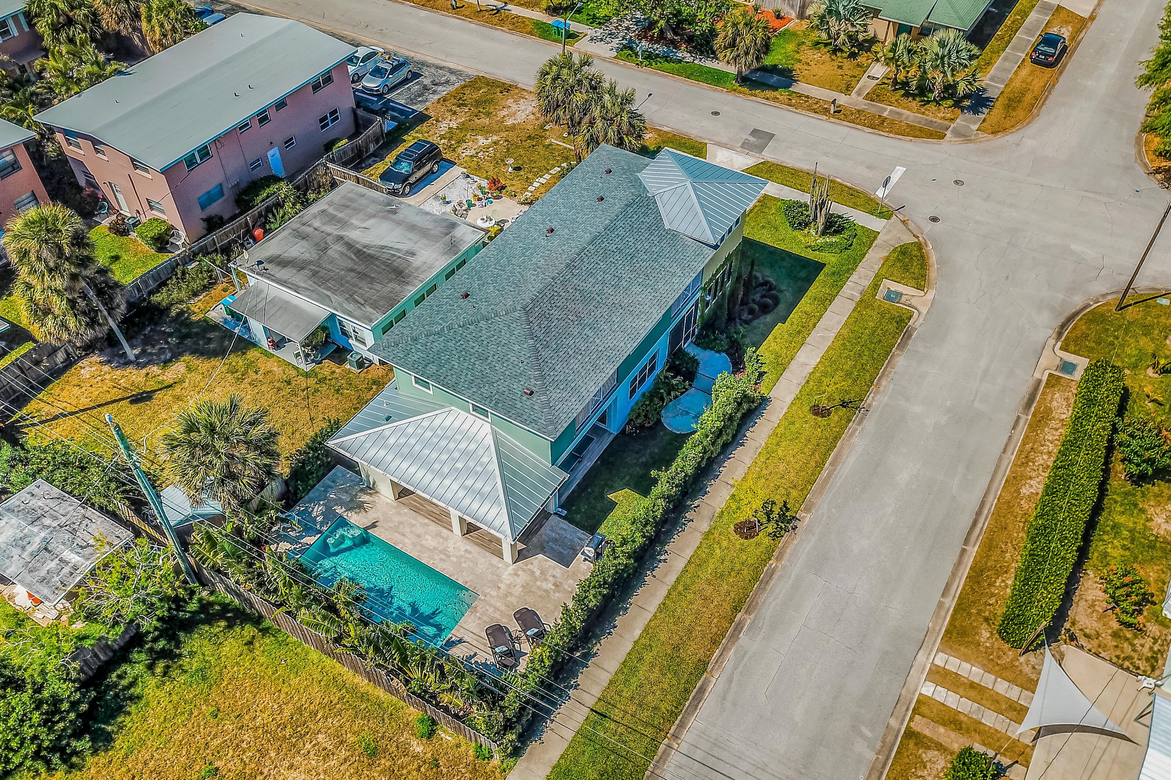 Vista aérea de una propiedad residencial con piscina, patio cubierto y césped bien cuidado.