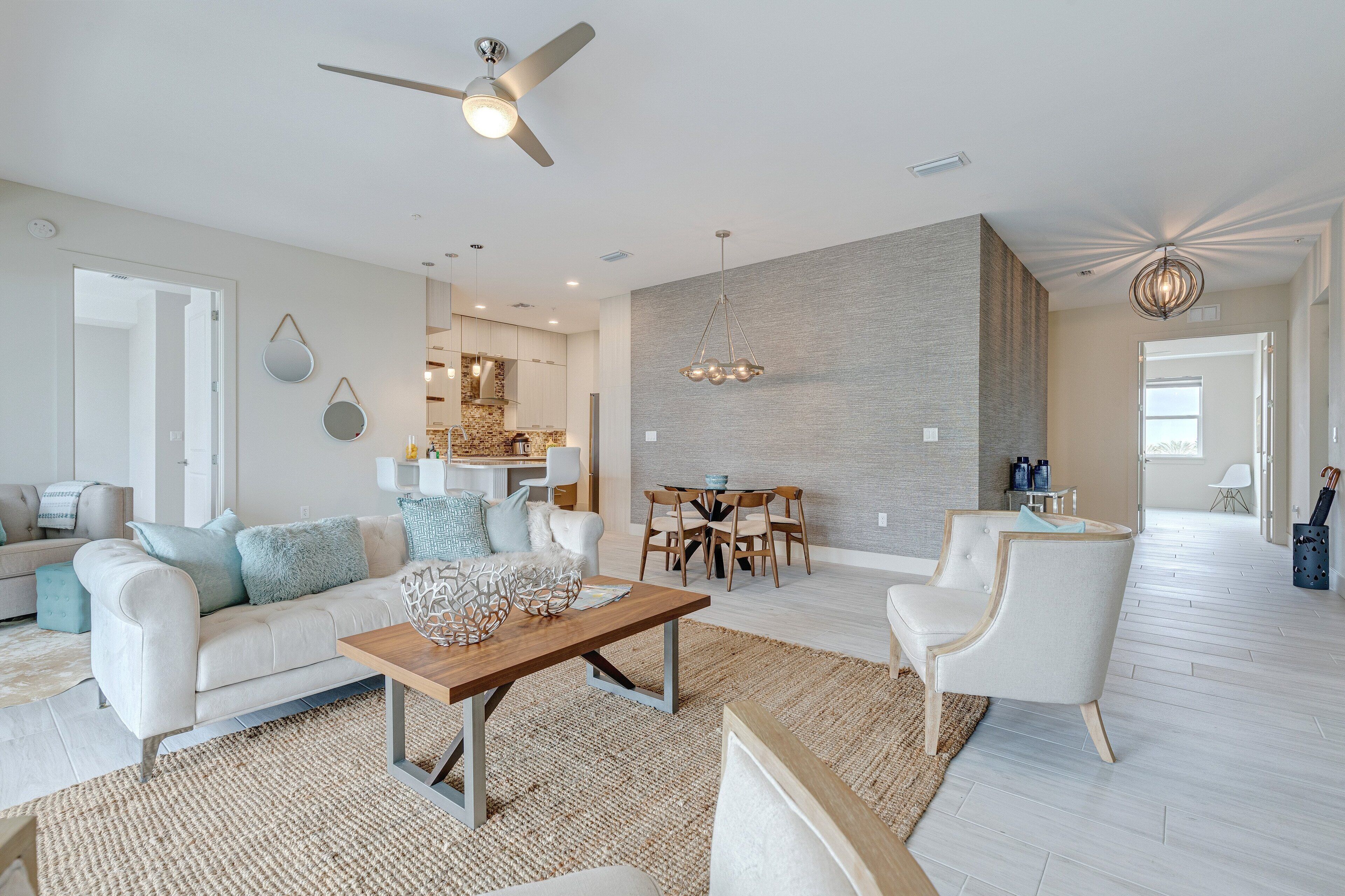 A spacious living room with a modern sofa, a wooden coffee table, and a dining area with a chandelier.