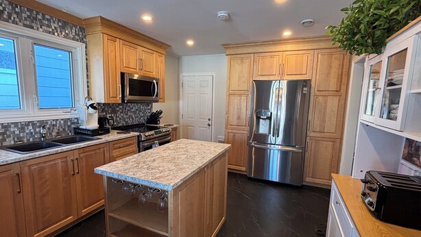 A modern kitchen with wooden cabinets, stainless steel appliances, a granite countertop, and a built-in wine rack. - 3BR Less then 5 minutes from Downtown, Hospitals & Mall (St. John's)