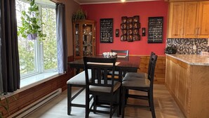 A dining area with a wooden table and chairs, a window with curtains, a cabinet with glassware, and a kitchen area with wooden cabinets. - 3BR Less then 5 minutes from Downtown, Hospitals & Mall (St. John's)