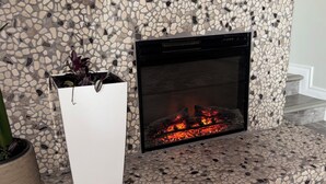 A fireplace with a mosaic surround, a white vase with a plant, and a wooden mantelpiece. - 3BR Less then 5 minutes from Downtown, Hospitals & Mall (St. John's)