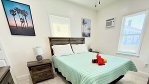 Een slaapkamer met een bed, nachtkastjes, een dressoir en kunst aan de wanden.