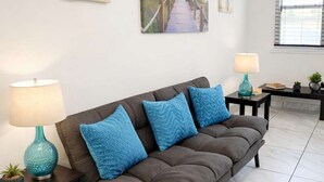 A living room with a sofa, two side tables with lamps, and artwork on the walls. - Hollywood Beach 1BR | 30 Sec to Sand + Kitchen (Hollywood)