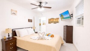 A hotel room with a bed, a nightstand, a TV, and a ceiling fan. - Hollywood Beach 1BR | 30 Sec to Sand + Kitchen (Hollywood)