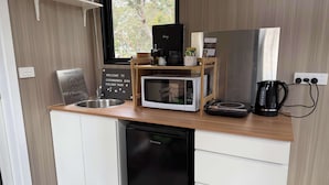 Pieni, käytännöllinen keittiönurkkaus, jossa on mikroaaltouuni, kahvinkeitin ja pieni pesuallas.