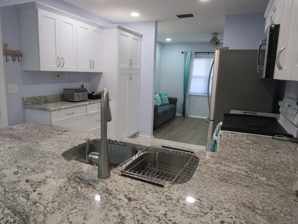 A kitchen with white cabinets, a granite countertop, a stainless steel sink, and a built-in oven.
