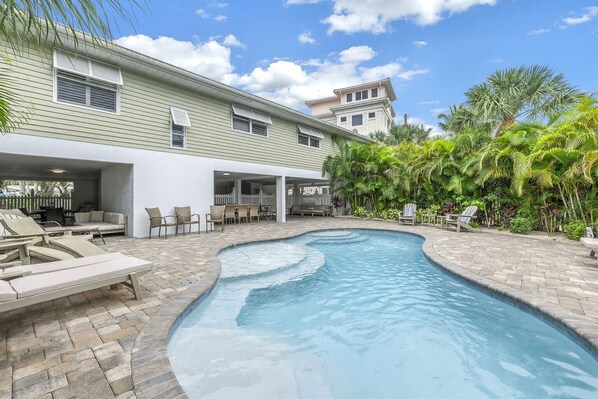 Une piscine avec des chaises longues et un espace patio couvert.