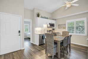 A modern kitchen with white cabinets, a microwave, and a dining area with wicker chairs. - Walking distance to Siesta Key Beach & Village w/Heated Pool & Outdoor Dining (Siesta Key)