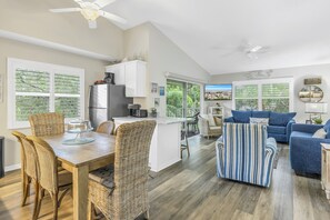 A spacious living area with a dining table, wicker chairs, a striped armchair, and a blue sofa. - Walking distance to Siesta Key Beach & Village w/Heated Pool & Outdoor Dining (Siesta Key)