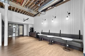 Ein modernes Interieur mit Holzboden, einer Sitzecke mit Tischen und einer Tür mit der Aufschrift '116'.
