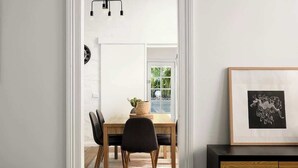 A dining area with a wooden table, black chairs, and a hanging light fixture. - Charming 2Bed Home Near Cafés & Racecourse (Hamilton)