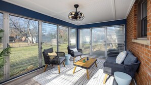 A sunroom with large sliding glass doors, wicker furniture, and a ceiling fan. - Clean & Cozy 4BR Retreat, Hot Tub, 1 Mile to DTP (Plymouth)