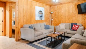 A cozy living room with two sofas, a coffee table, and a ceiling fan. - Bixby Cove Cabin #1 (Porum)
