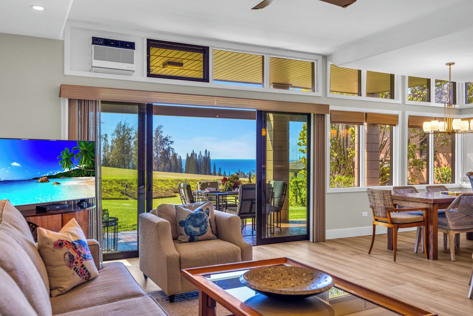 A spacious living room with a large TV, comfortable seating, and a view of a golf course.