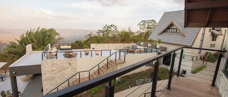 A modern outdoor terrace with stone walls, a wooden deck, and a view of distant mountains.