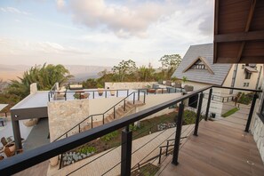 A modern outdoor terrace with stone walls, a wooden deck, and a view of distant mountains. - Villa Real Chalés (Viçosa do Ceará)