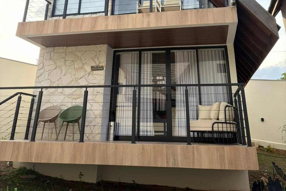 A two-story house with a stone facade, large windows, and a balcony with outdoor seating.