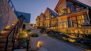 A modern hotel with a stone facade, multiple balconies, and a well-lit pathway leading to the entrance. - Villa Real Chalés (Viçosa do Ceará)