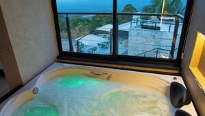 A hot tub with a view of the ocean and a balcony with outdoor furniture. - Villa Real Chalés (Viçosa do Ceará)