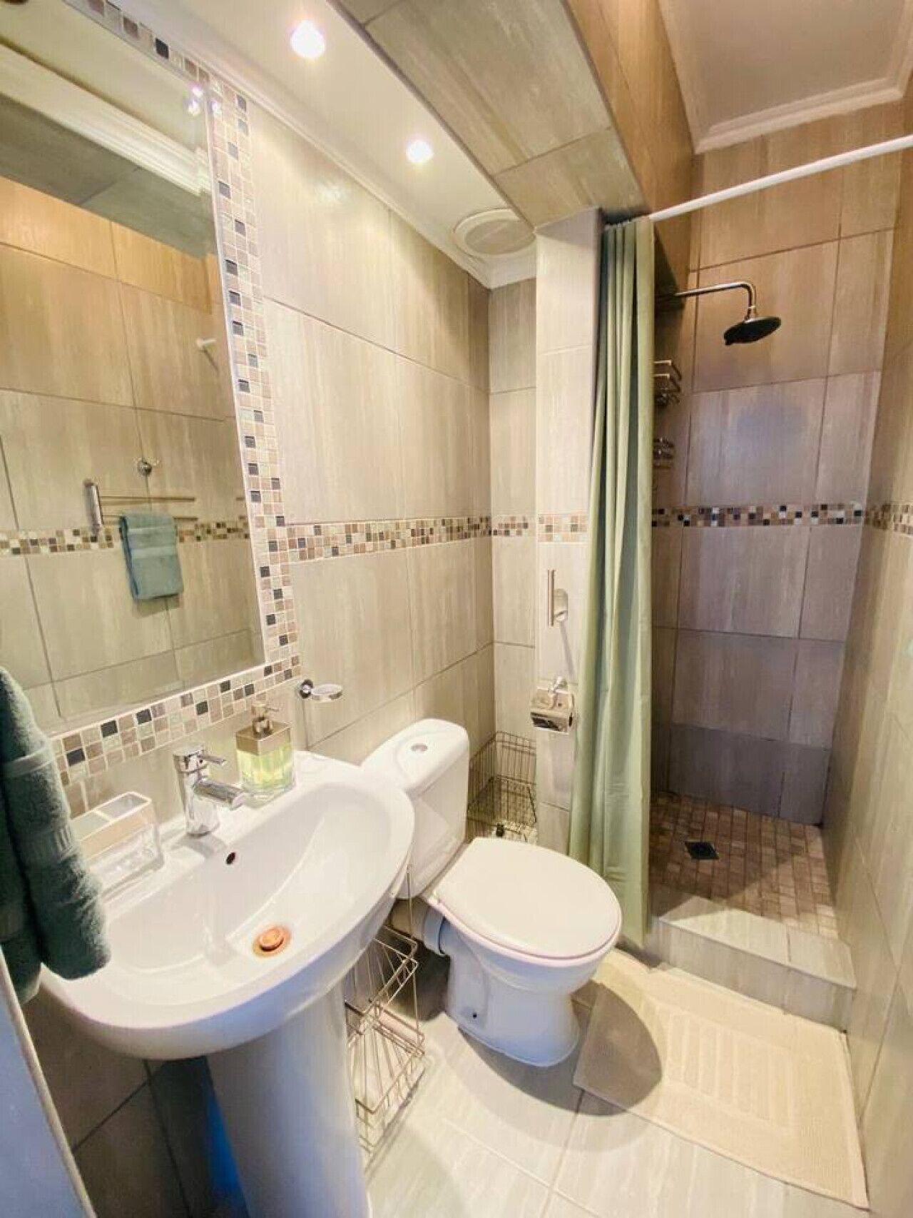Ein Badezimmer mit Toilette, Waschbecken, Dusche und gefliesten Wänden.